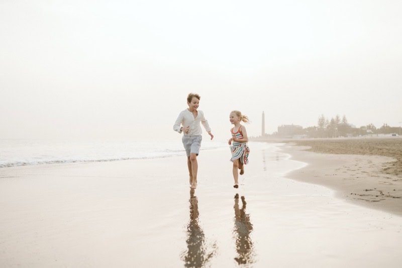 Niños corriendo por la orilla del mar